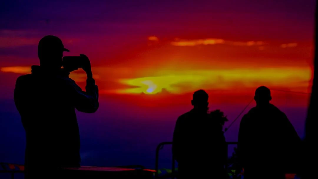Friends silhouetted against a colourful sunset